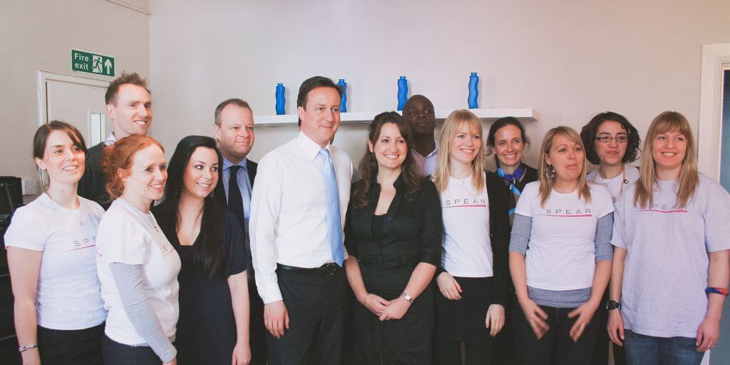 David Cameron in suit smiling with group of people